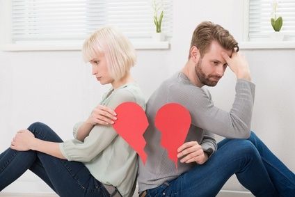 Sad Couple Sitting Back To Back Holding Red Broken Heart