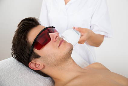 Young Man Receiving Laser Hair Removal Treatment At Beauty Center